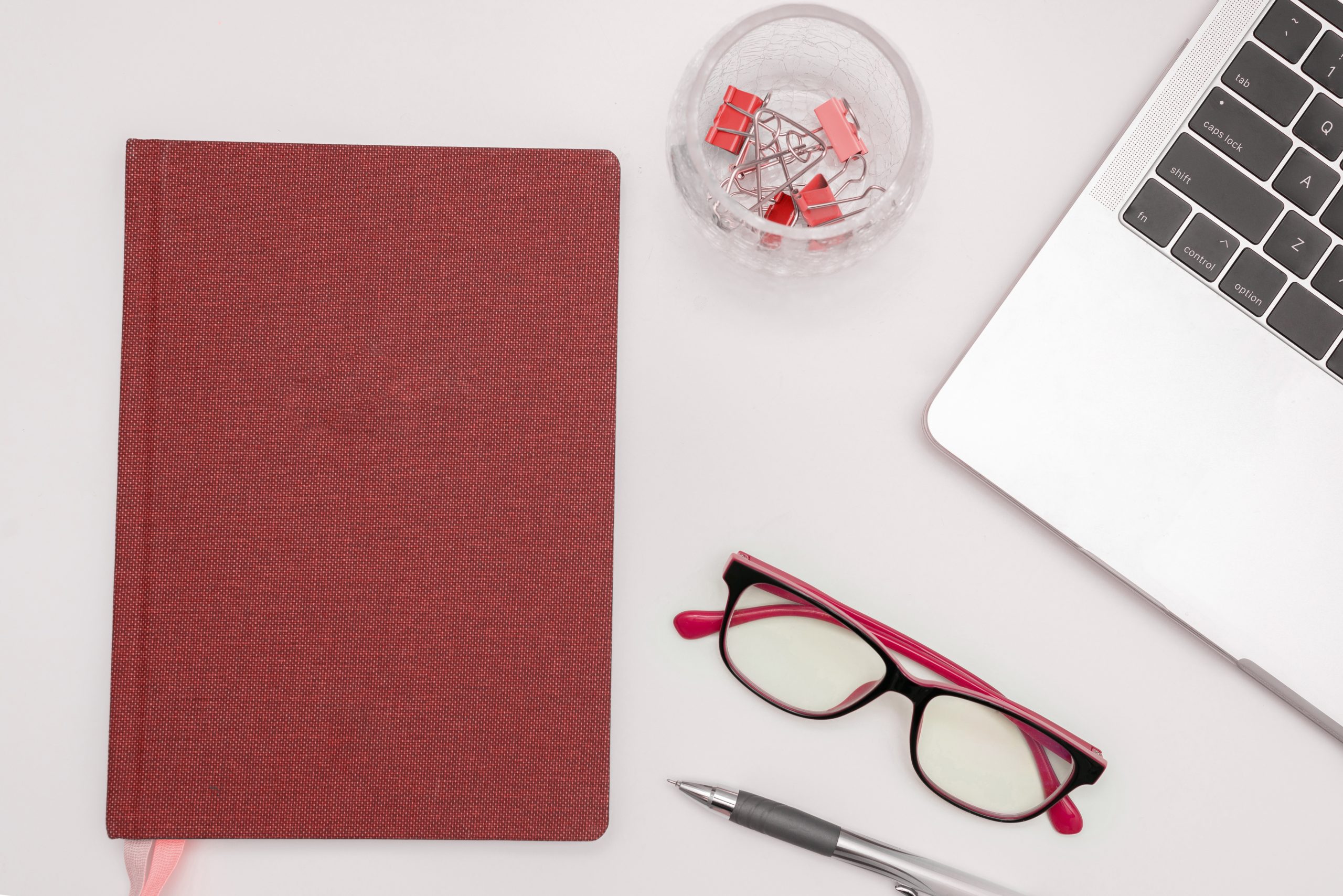 Office Supplies Over Desk With Keyboard And Glasses And Coffee Cup For Working Remotely, Assorted School Utilities For Studying With Hot Drink And Eyeglasses.